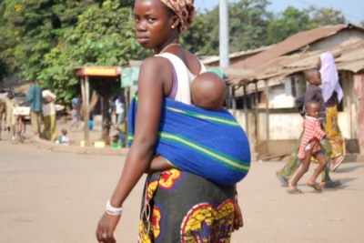 A young woman carries her baby in Conakry.