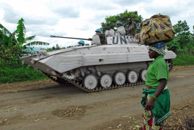 A UN armored-personnel carrier glides by a Congolese woman just south of the flashpoint village of Rutshuru, which lies roughly 65 km north of the provincial city of Goma (file photo).