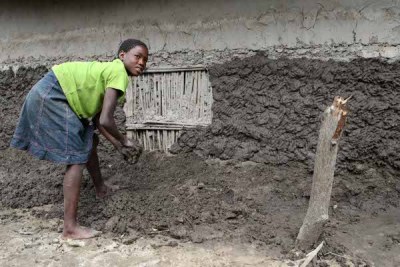 Inonga Mubita (14) uses clay and mud to rebuild the walls of her family's flood damaged hut. Effects of the seasonal flooding of the Zambezi River in Zambia's Western Province.