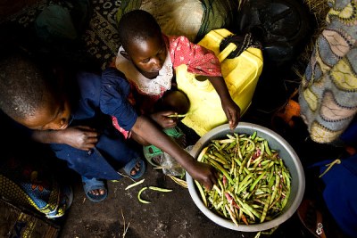 Children shell their family's monthly 10kg-ration of beans inside their home at Buhimbe Camp near Goma in North Kivu, DRC.