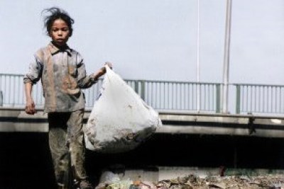 A young girl carries a bag of recyclables.