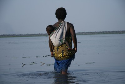 The wife of a fisherman wades out to meet her husband returning from fishing in the Zambezi River near Mopeia in Mozambique.