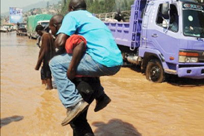 A man is carried across the flooded Nyabugogo highway.