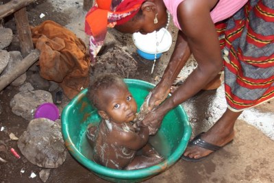 A mother washes her child in Kroo Bay slum in Freetown, where access to basic sanitation is severely limited and cholera outbreaks are regular occurrences.