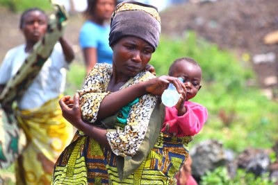 Une femme donnant de l'eau à son bébé dans un camp de réfugiés en RDC.