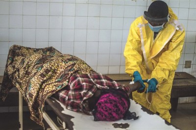 Un employé dans un centre de traitement contre la maladie à virus Ebola en Sierra Leone prend soin d’une malade.