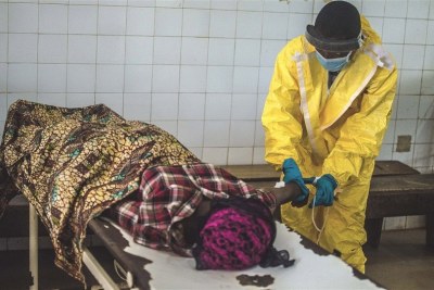 Un employé dans un centre de traitement contre la maladie à virus Ebola en Sierra Leone prend soin d’une malade.
