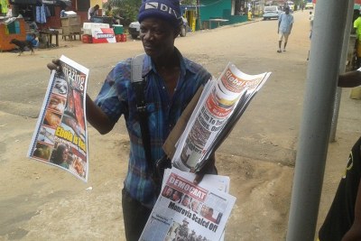 A newspaper vendor sells Monrovia's dailies, dominated by Ebola news.
