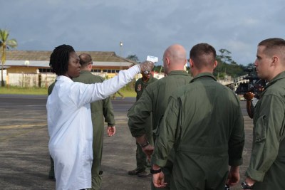 Marines from the Special Purpose Marine Air Ground Task Force Crises Response 14-2, out of Moron, Spain stand in line to have their temperature checked as they exit the KC-130 that brought them to Monrovia.