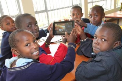 School children hold up one of the Samsung tablets used at the library.