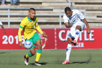 Seturumane Tsepo of Lesotho takes a shot at goal while challenged by Rivaldo Coetzee of South Africa during the 2016 Cosafa Cup Quarterfinals match