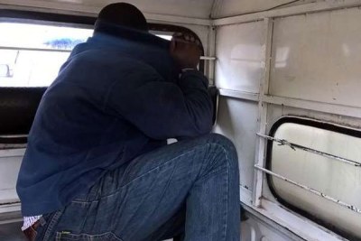 Emmanuel Peter Enobemhe hides from the camera at Kayole Police station after he was arrested by Anti-Terror Police.