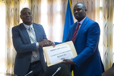 Isaac Munyakazi, the minister of state for primary and secondary education (L) receives O-Level results from Janvier Gasana, the director-general of Rwanda Education Board.
