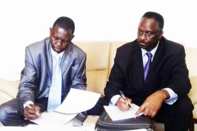 Col Kaka (left) signs documents during the handover of office in Kampala early this week. Looking on is Brig Ronnie Balya, the outgoing ISO director.