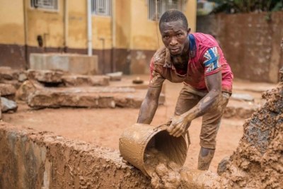 Five days after the mudslide in Sierra Leone, a resident is still moving mud from his home.