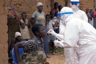 A member of the World Health Organisation takes an oral sample from a patient suspected of having Marburg haemorrhagic fever.