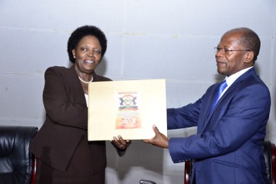 Uganda National Examinations Board chairperson Professor Mary Okwakol hands the 2017 Uganda Advanced Certificate of Education Examination results to State Minister for Higher Education Dr John Chrysostom Muyingo, right, in Kampala on February 21, 2018.