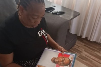Torkwase Kuraun, Sister of missing journalist Tordue Salem, looks at pictures of him in the family photo album at her home in Abuja, Nov. 4, 2021.